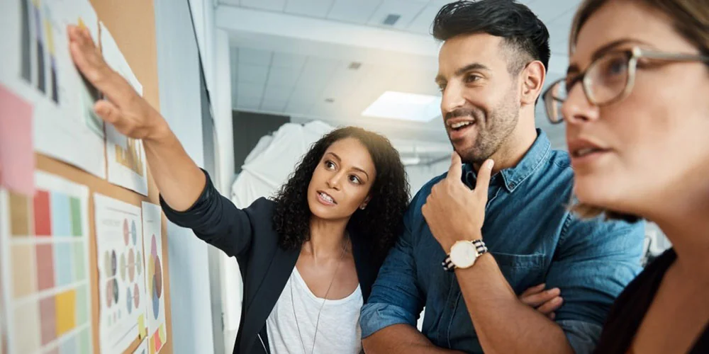 Group of three people reviewing a whiteboard
