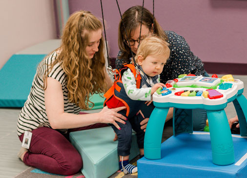 A woman practicing physical therapy on a baby