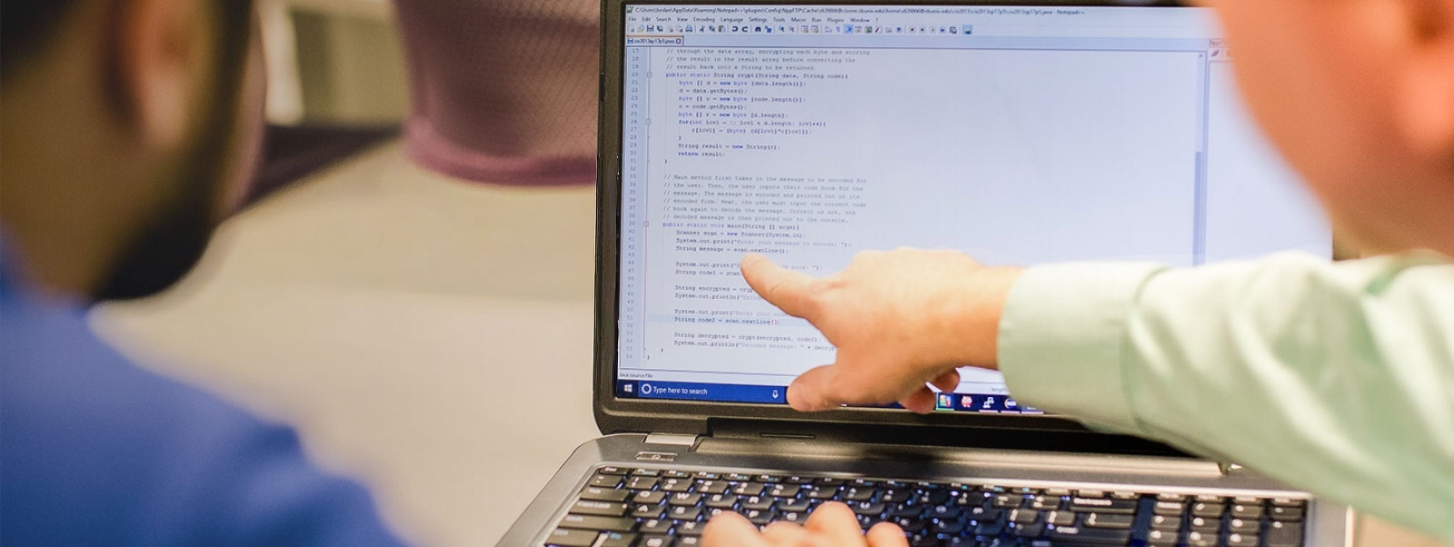 Two young men working together on a laptop