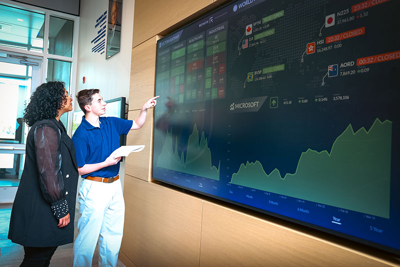 Two people reviewing a large screen of analytical data