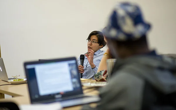 A person sitting in class speaking into a microphone.