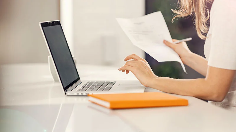Someone's arm approaching an open laptop on a desk.