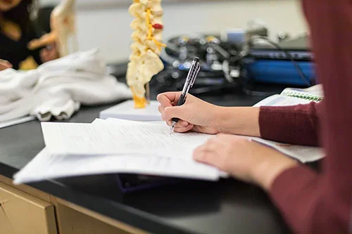 A nursing student writing in a notebook