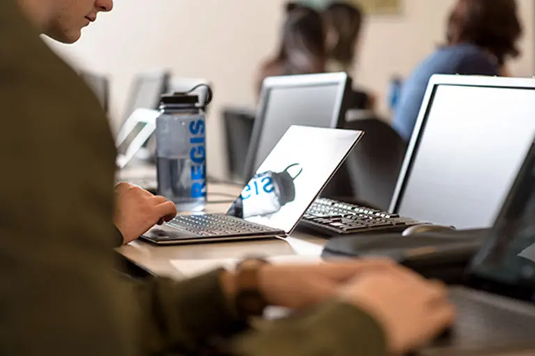 Students in class typing on laptops