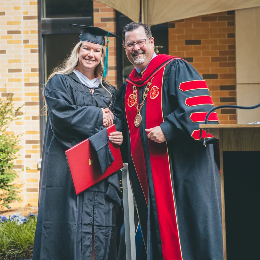 A Bryan College graduate shaking hands while receiving a diploma
