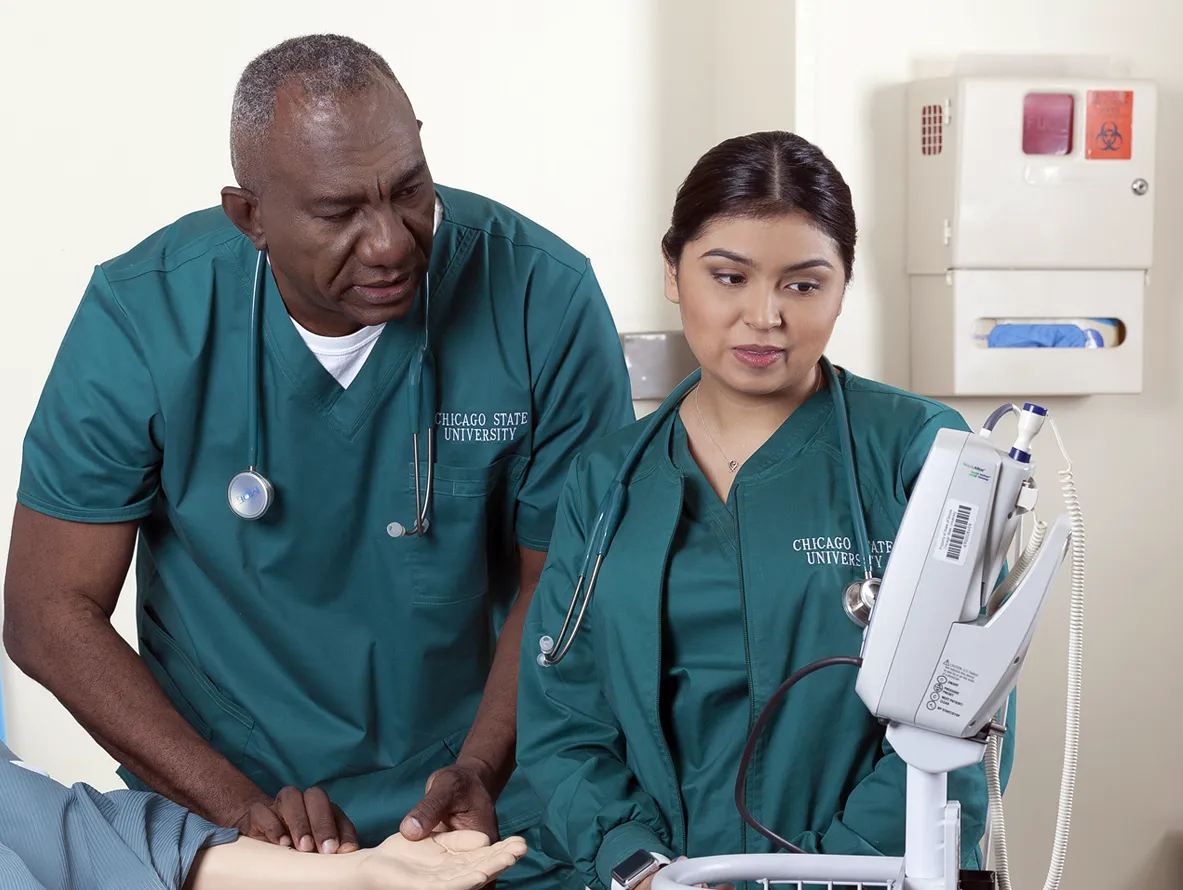 Two clinicians in scrubs reviewing patient care information together.