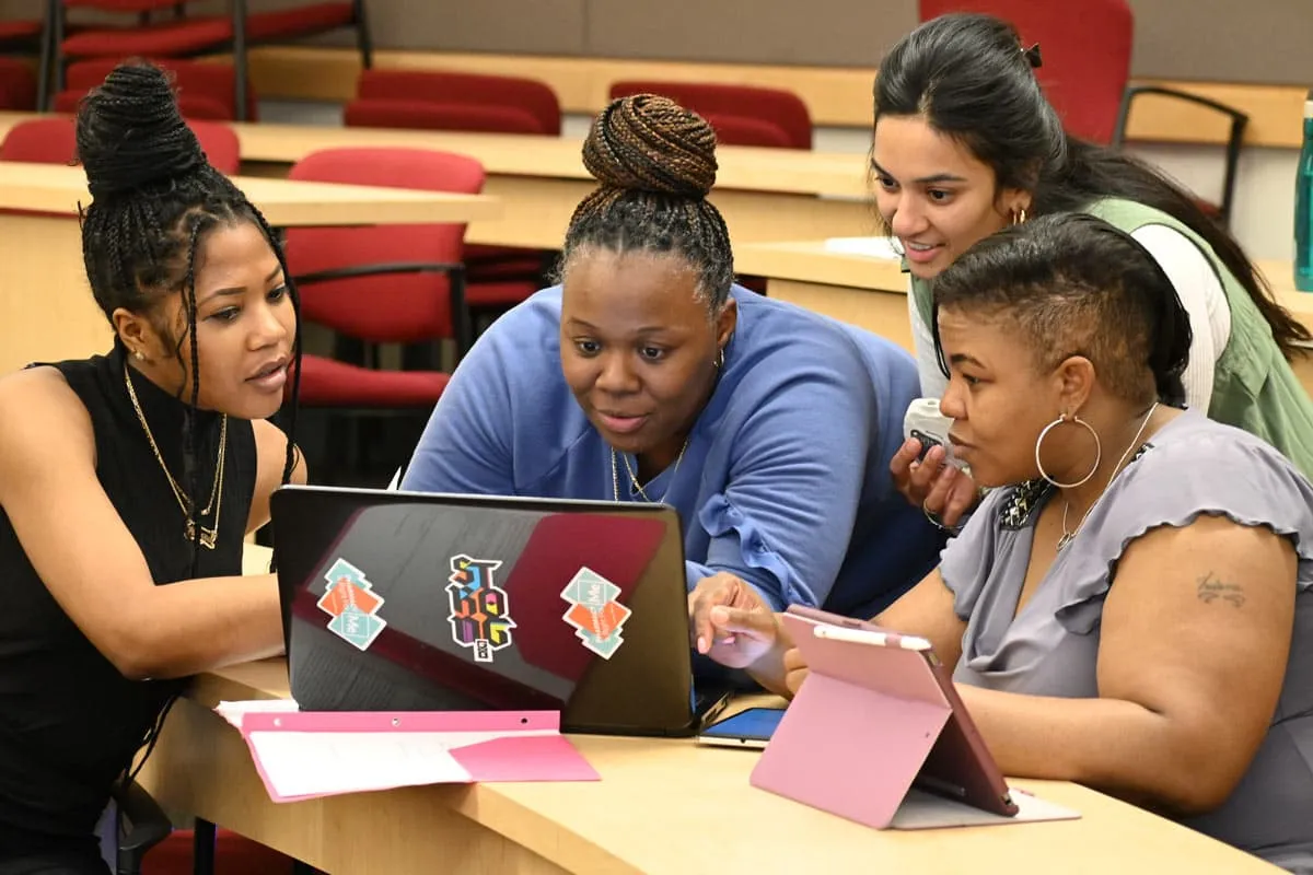 Students collaborating with laptops in a classroom.