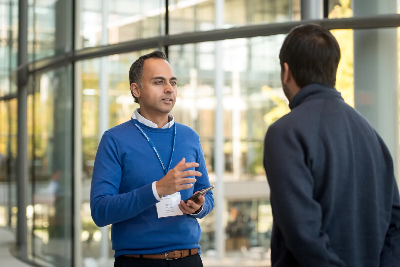 Two people in conversation inside a building with windows